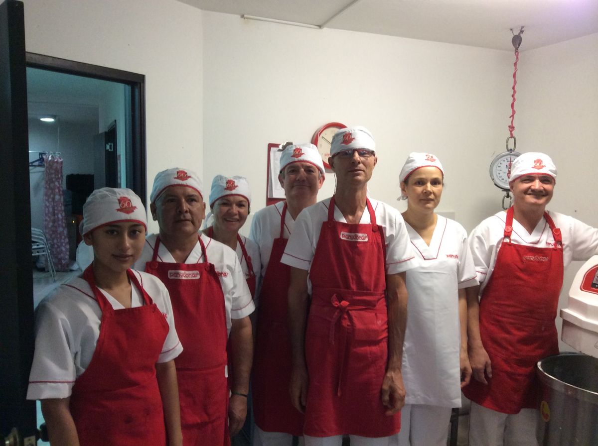 Equipo de Panydonas con delantales rojos en la planta de producción